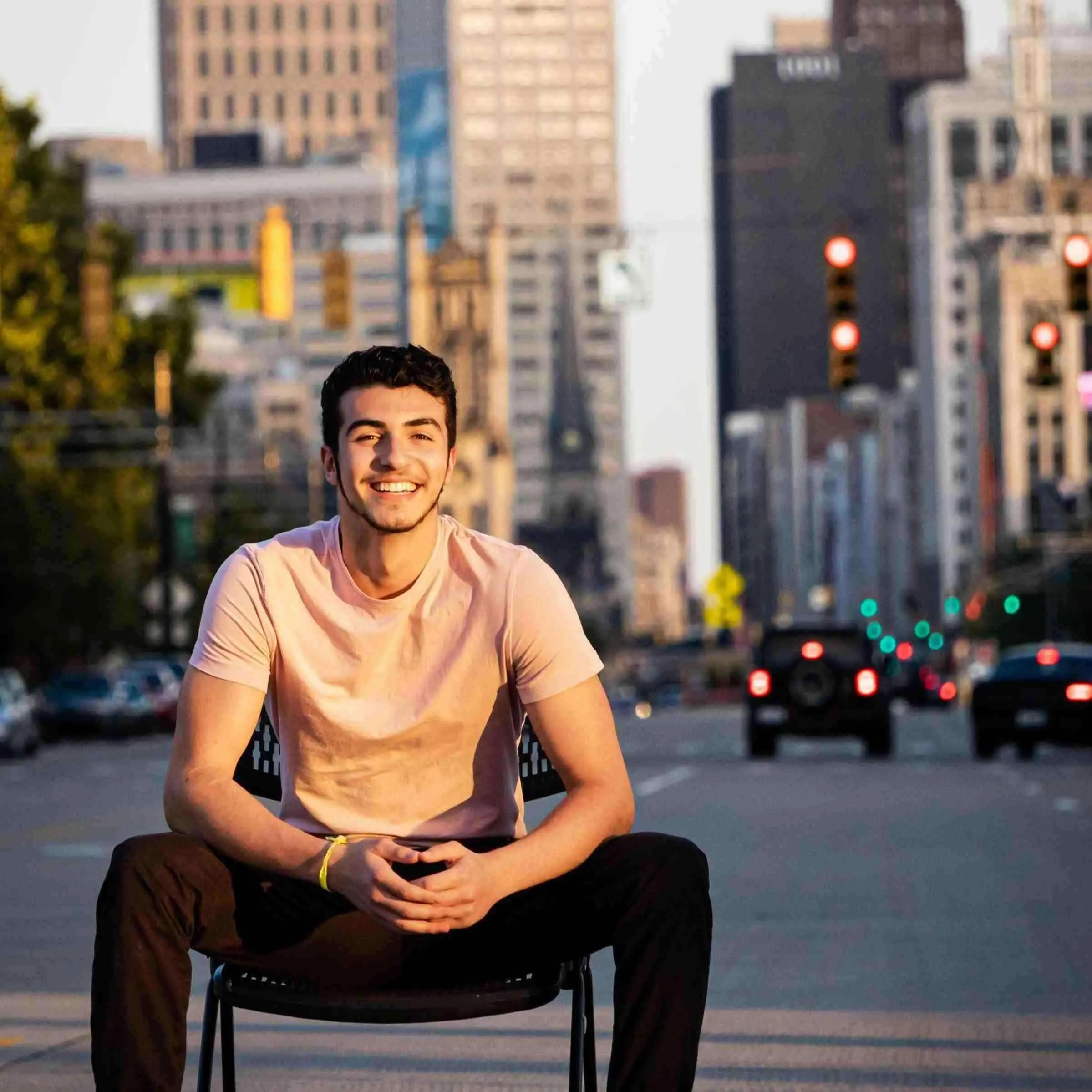 Young man sitting on a chair on a Detroit city street with skyscrapers in the background
